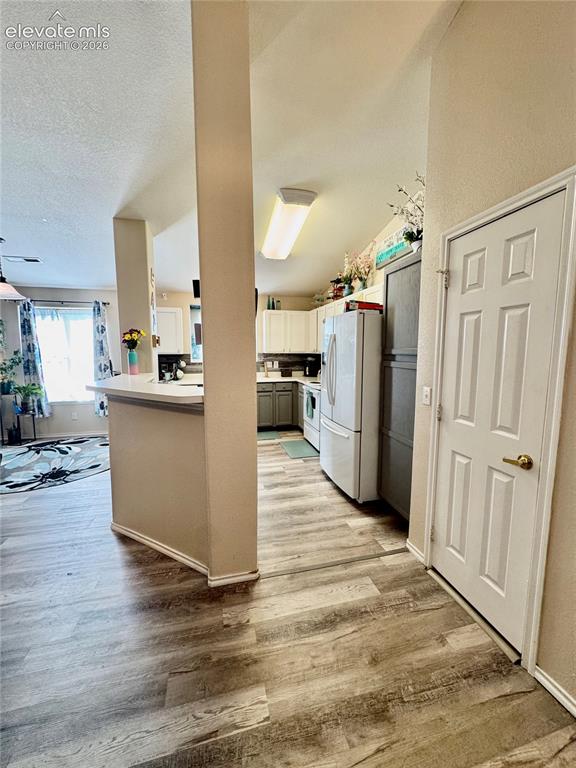 Image 4 of 32: Kitchen and living area featuring wood-finish flooring, white cabinetry, an