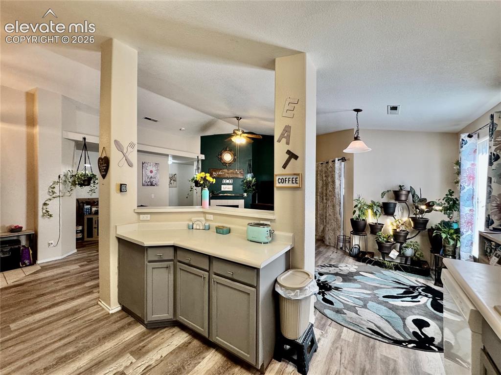 Image 7 of 32: Kitchen featuring light-toned countertops, gray cabinetry, and wood-finish