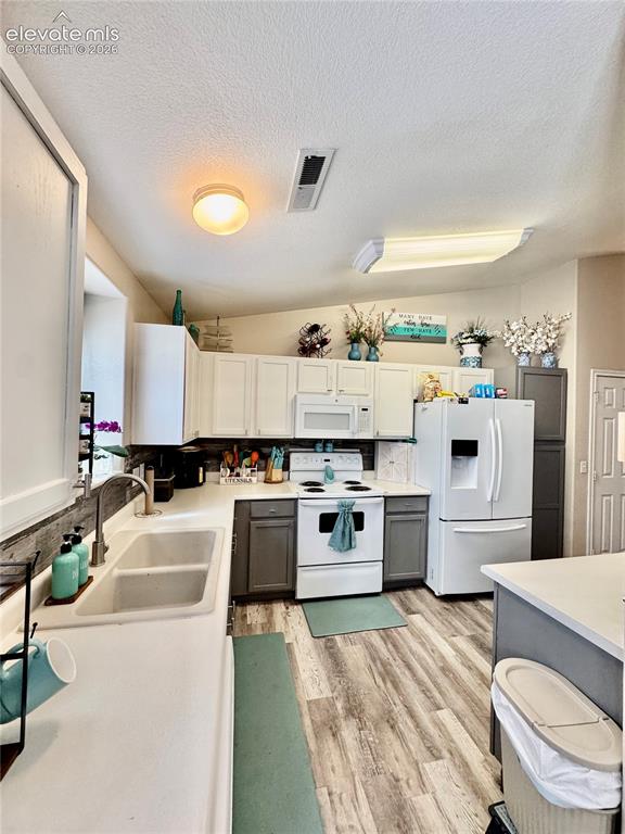 Image 8 of 32: Kitchen featuring a double basin sink, wood-finish flooring, white applianc
