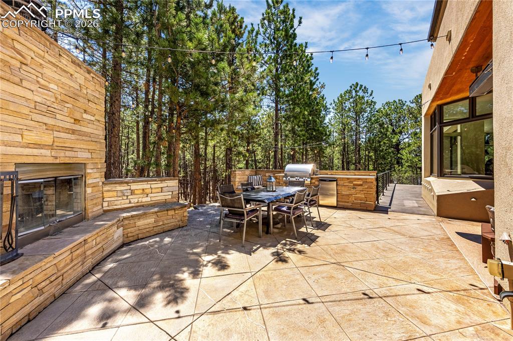 Image 18 of 48: Side patio with built-in grill & fireplace