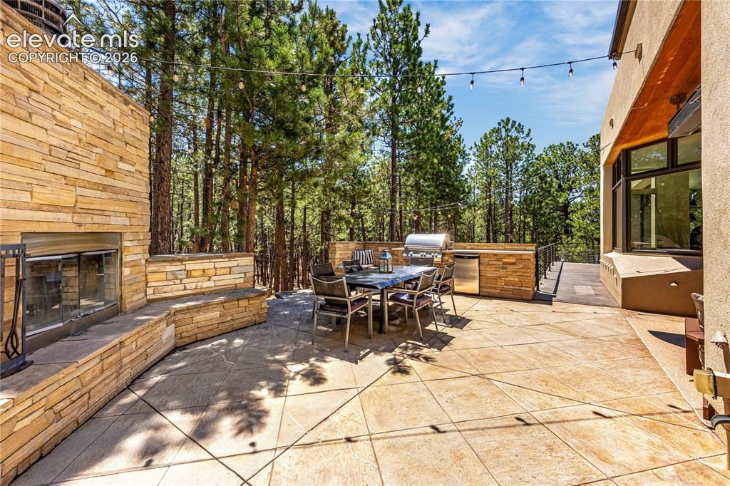 Image 19 of 49: Side patio with built-in grill & fireplace