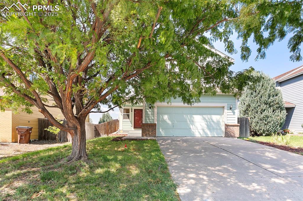 Image 2 of 29: Front of house featuring 2-car garage and mature tree