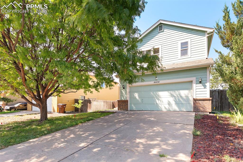 Image 3 of 29: Front of house featuring 2-car garage and mature tree