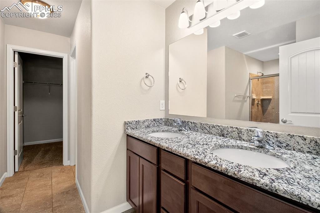 Image 14 of 39: Primary bathroom with dual vanity surrounded by granite counter tops, a wal