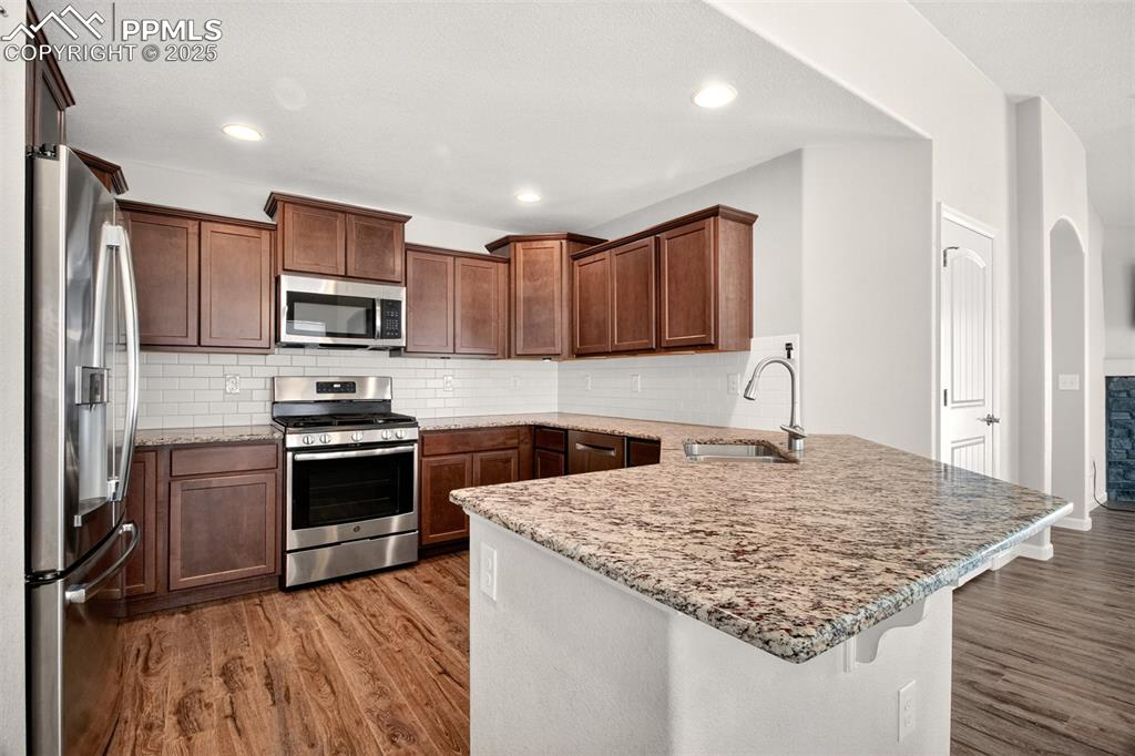 Image 8 of 39: Kitchen with gas stove, matching stainless appliances, breakfast bar and gr