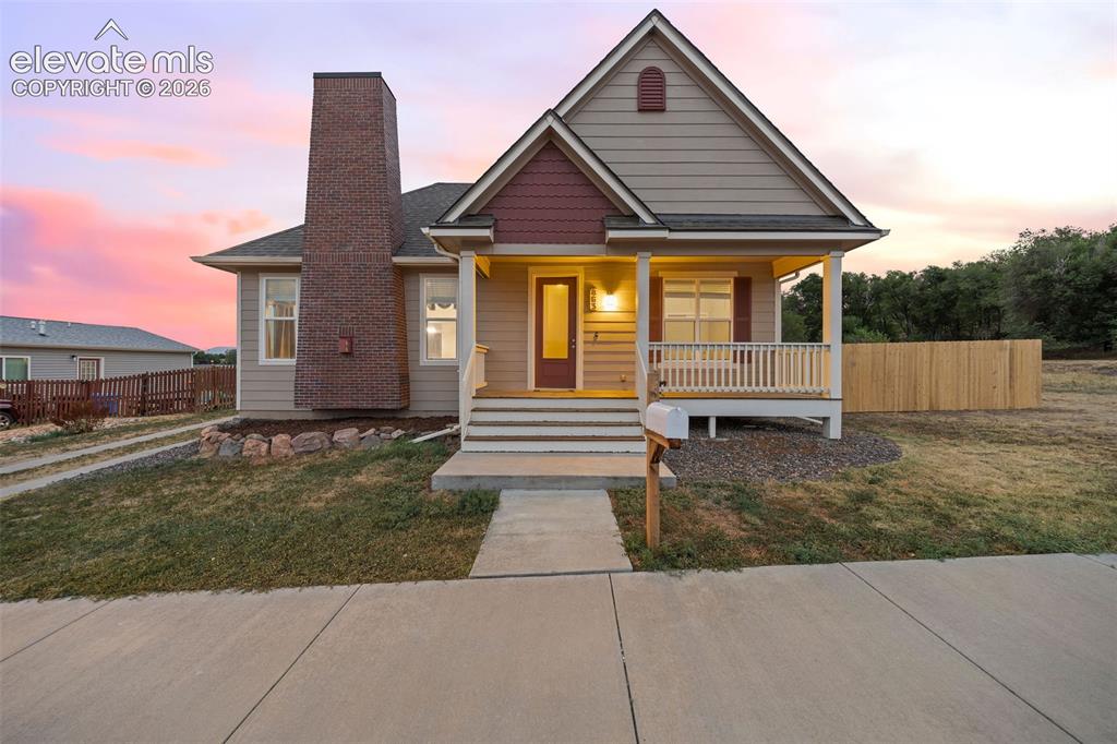 Caption: Charming Craftsman-style home featuring a welcoming covered front porch, classic brick chimney, gabl