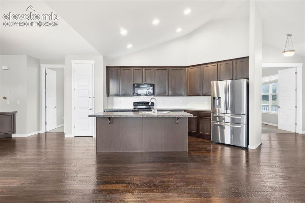 Image 14 of 39: Open-concept living area featuring engineered wood flooring, soaring vaulte