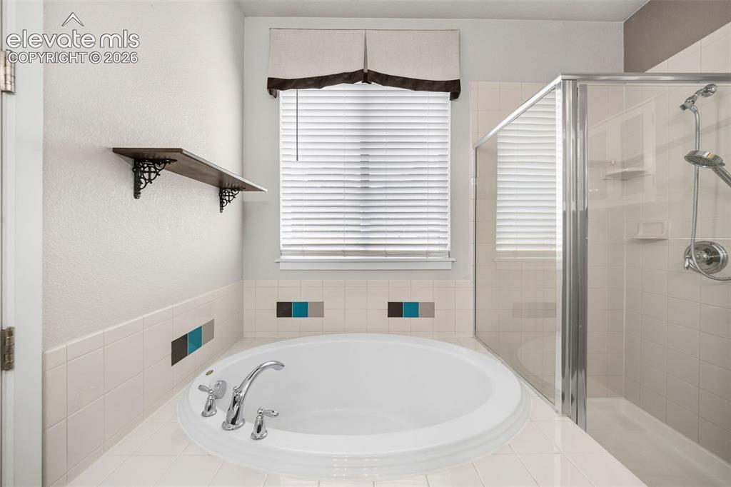 Image 24 of 39: Bathroom featuring a tub and shower combination with a white tile surround,