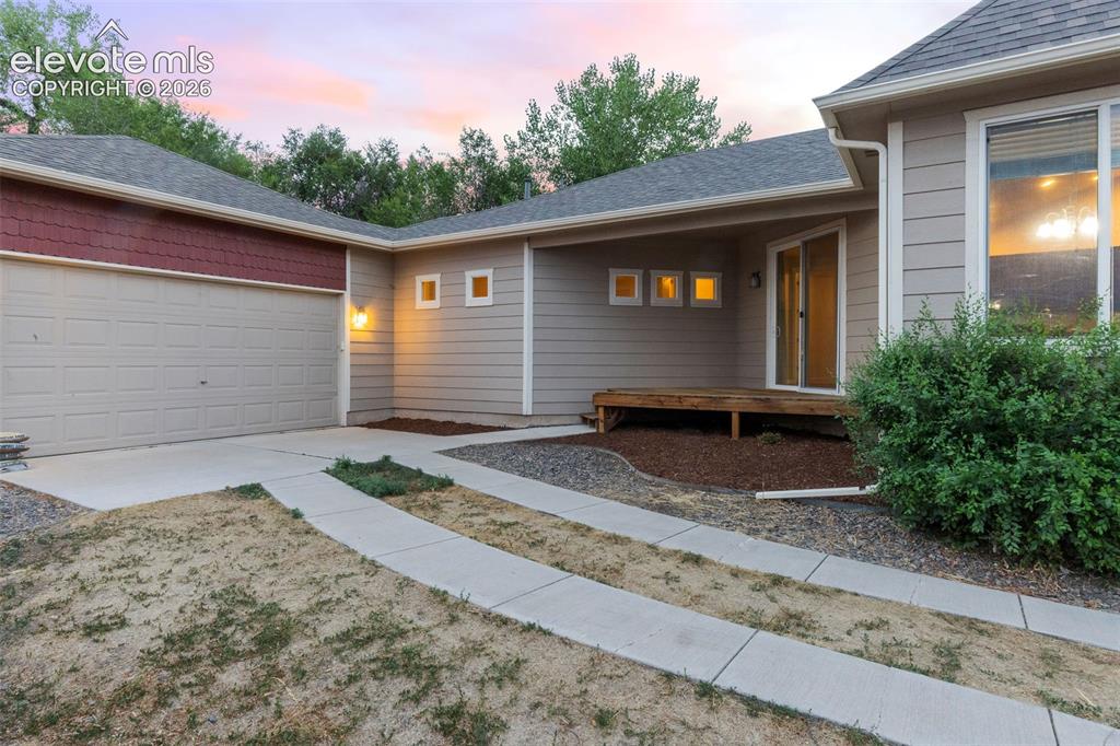 Image 37 of 39: Welcoming covered front porch featuring wood decking, classic white railing