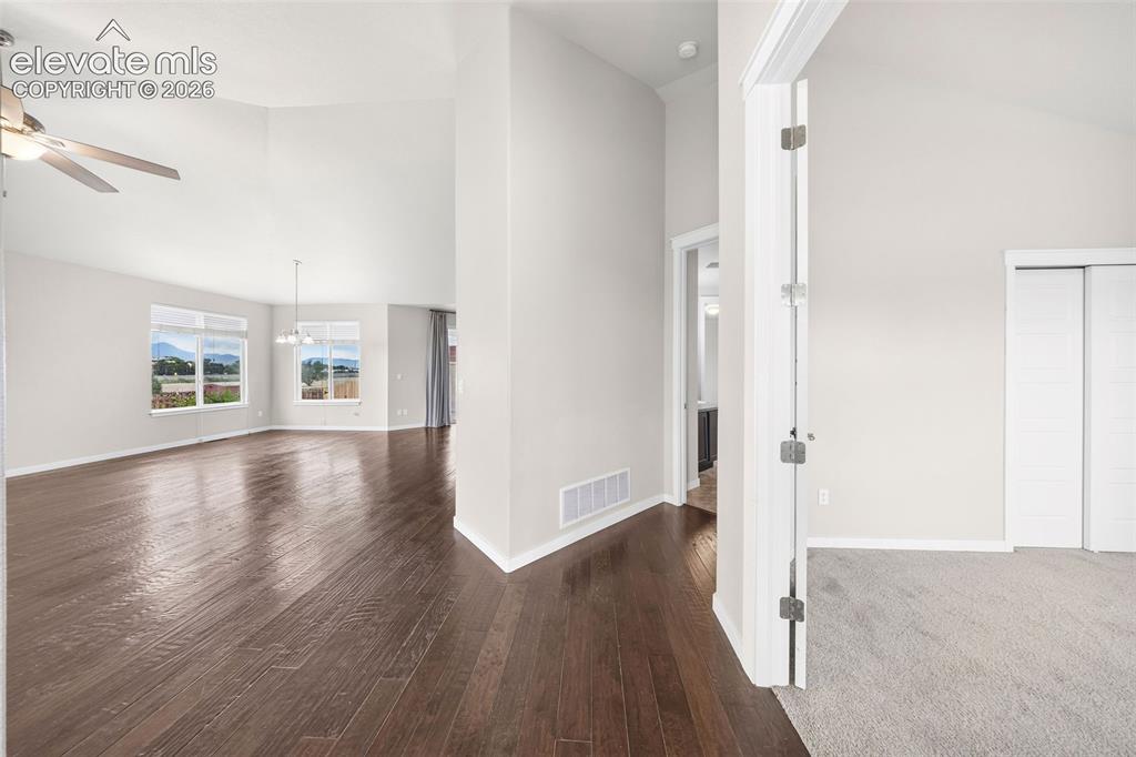 Image 7 of 39: Spacious living area featuring soaring vaulted ceilings, engineered wood fl