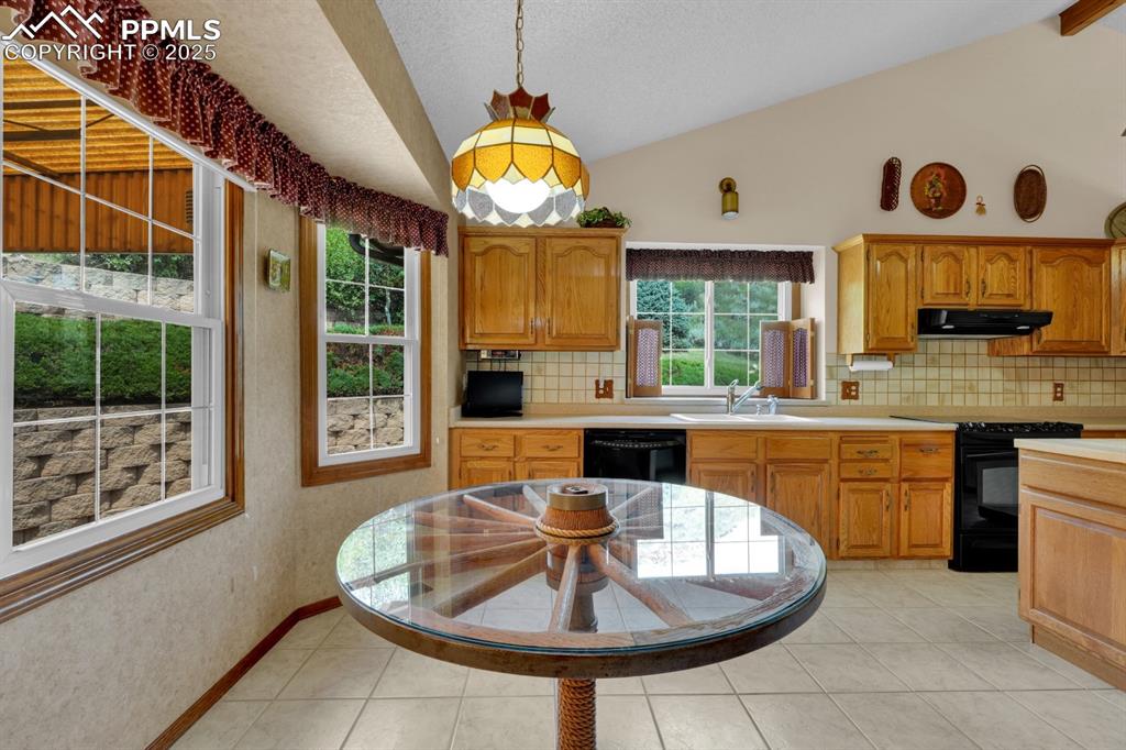 Image 12 of 47: Kitchen featuring decorative backsplash, light countertops, black appliance