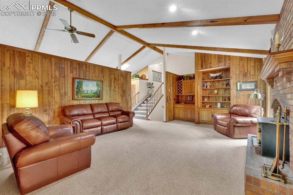 Image 13 of 47: Living room featuring pine wood wood paneling and exposed beams 