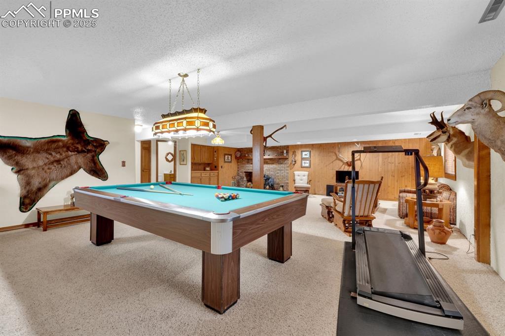 Image 27 of 47: Game room with carpet floors, billiards, a fireplace, a textured ceiling, a