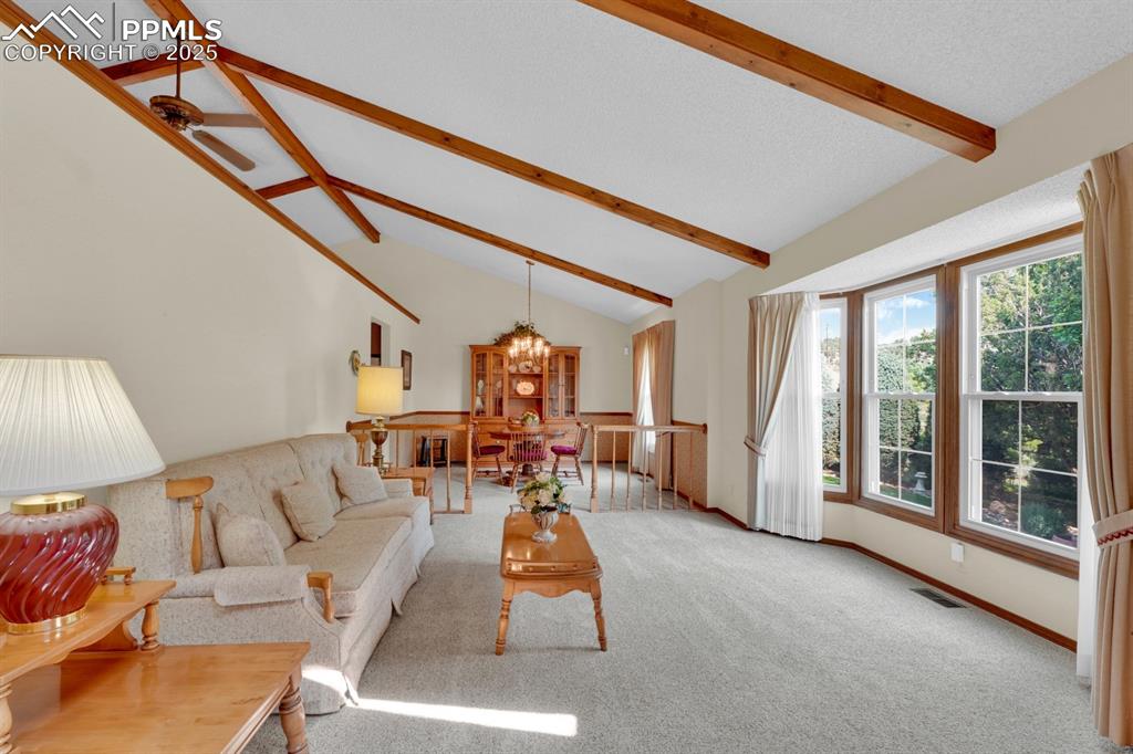 Image 6 of 47: Living area with exposed beams and high vaulted ceiling