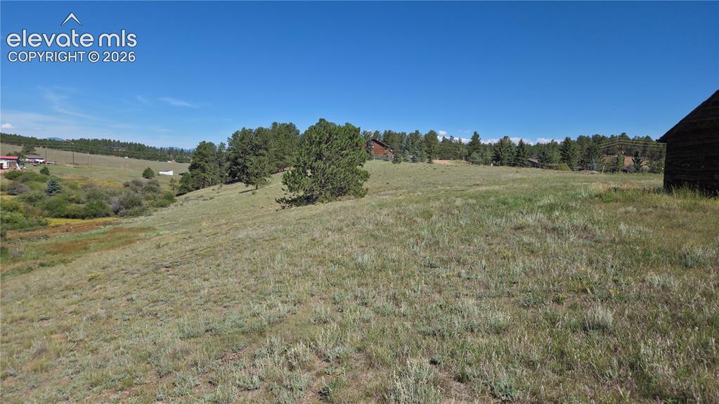Image 13 of 35: Expansive open land featuring diverse natural vegetation and a few scattere