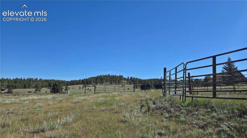 Image 14 of 35: View from lot looking toward metal gate and hills in the background.
