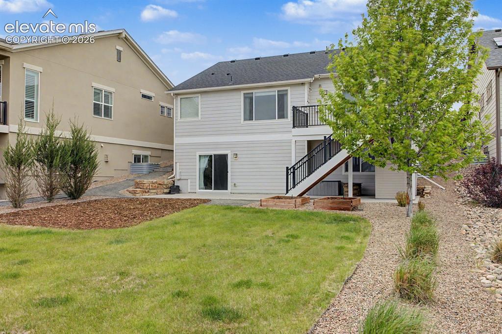 Image 18 of 44: Rear exterior featuring a second-story deck with black railings, a ground-l