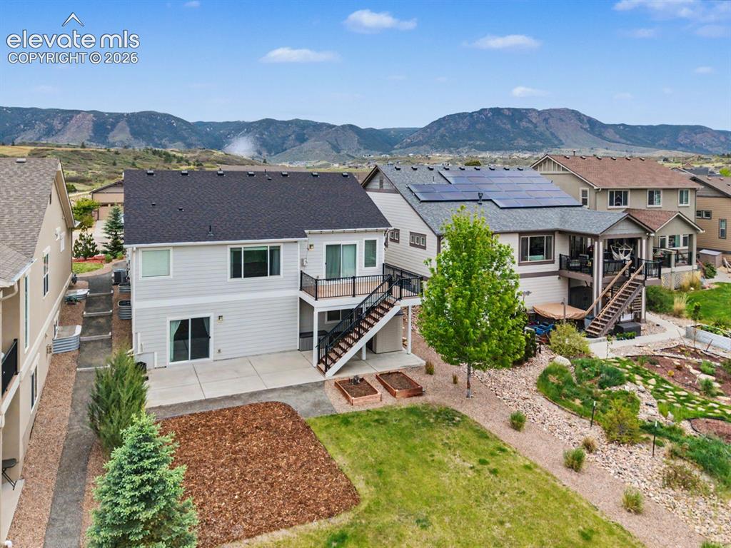 Image 2 of 44: Rear exterior featuring a ground-level patio, upper-level deck with black r