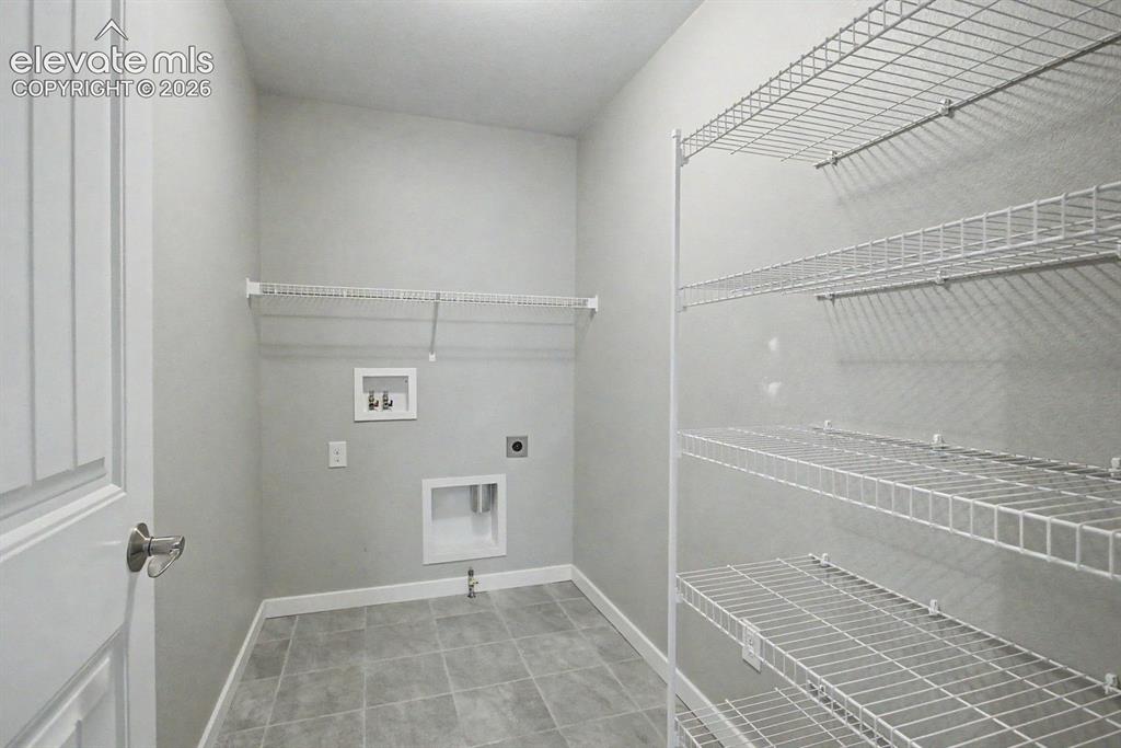 Image 23 of 44: Utility room featuring a paneled door with brushed nickel hardware, light g