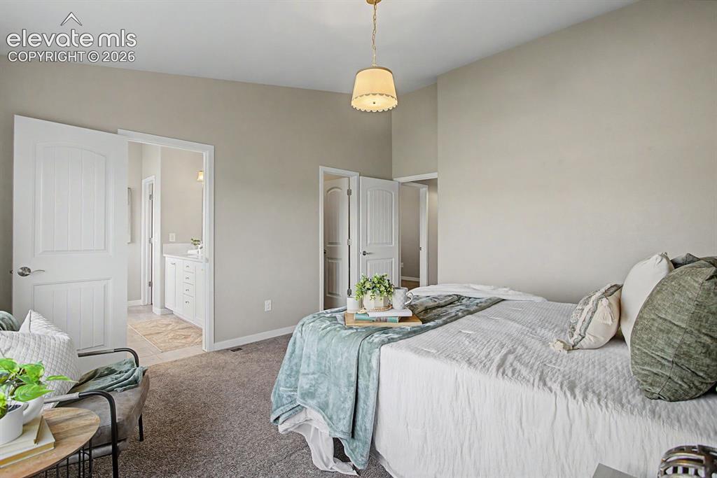 Image 25 of 44: Carpeted room with light neutral walls and a decorative ceiling light fixtu