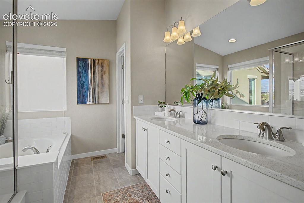 Image 26 of 44: Bathroom featuring a double vanity with stone countertops, white cabinetry,