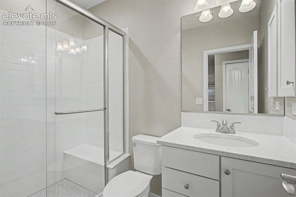 Image 36 of 44: Shower enclosure with white subway tile, built-in bench, and hexagonal mosa