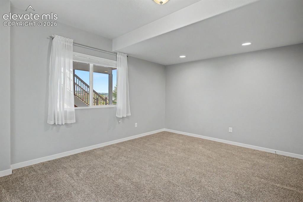 Image 37 of 44: Spacious room featuring neutral carpeting, light gray walls, a window with
