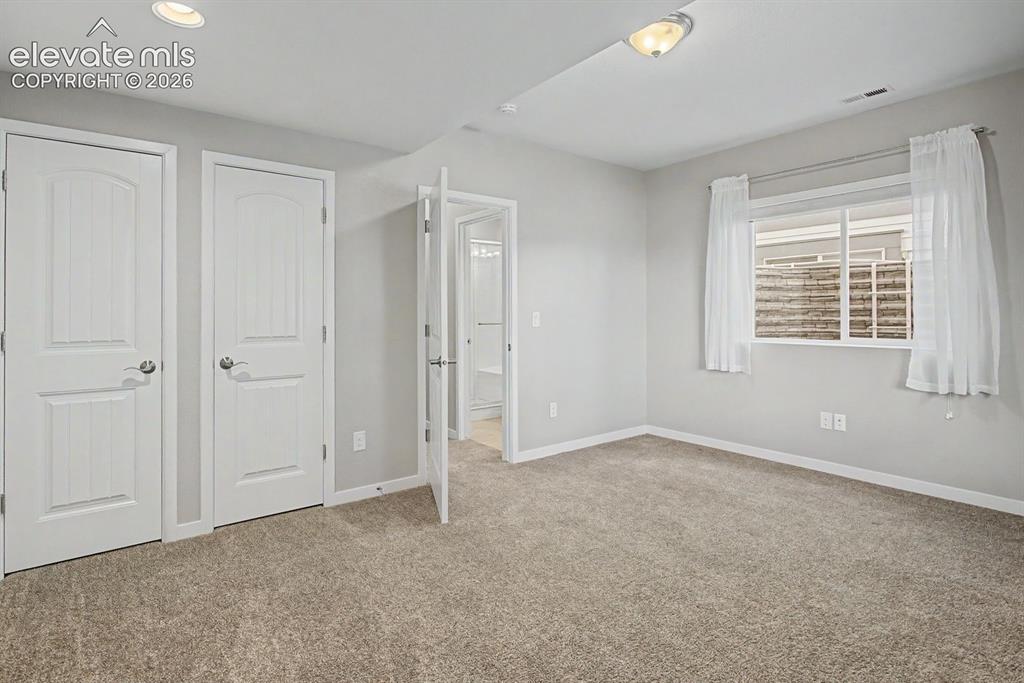 Image 38 of 44: Carpeted room featuring two panel doors, a window with white trim, and a se