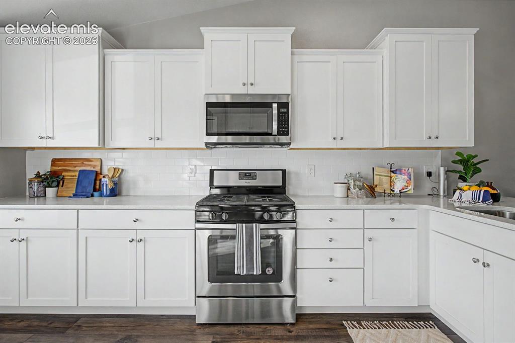 Image 4 of 44: Contemporary kitchen featuring white shaker cabinetry, stainless steel appl