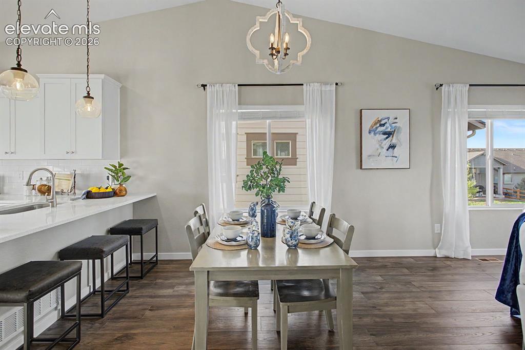 Image 5 of 44: Open-concept living area featuring a vaulted ceiling and wood-finish floori
