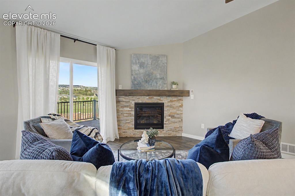 Image 7 of 44: Living area featuring a stone-clad fireplace with a wood mantel, wood-finis