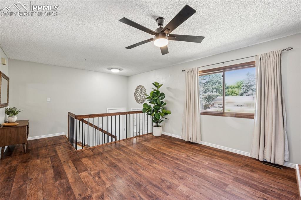 Image 10 of 44: Living room view towards entry, newer LVP flooring, new ceiling fan and cur
