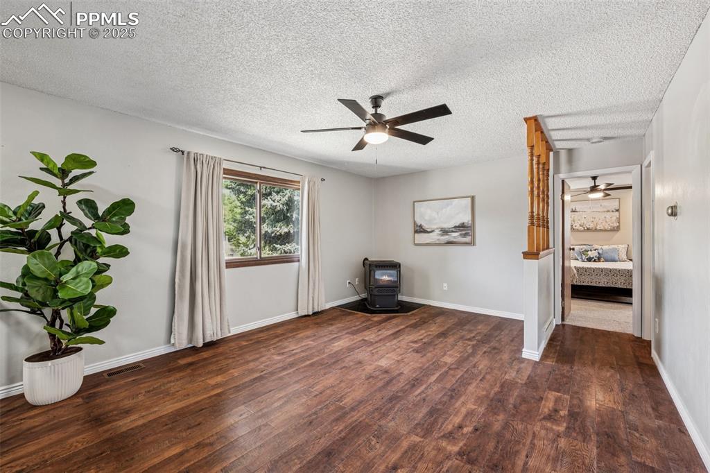 Image 2 of 44: Living Room upper level, newer LVP flooring, curtains, and pellet stove, ne