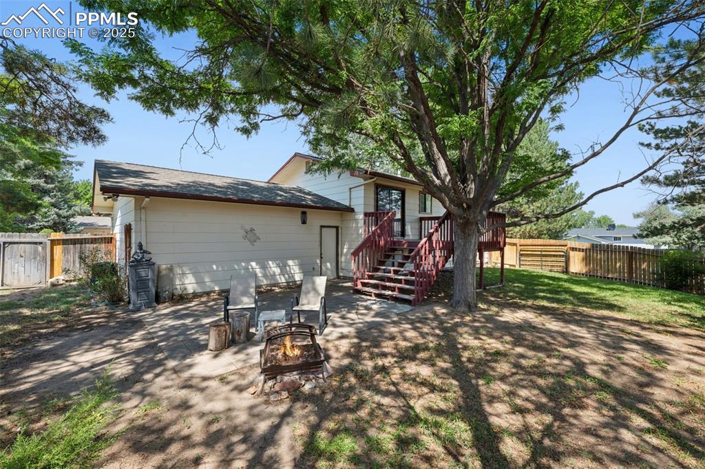 Image 37 of 44: Side yard view towards door to garage and deck and paver area. Large side