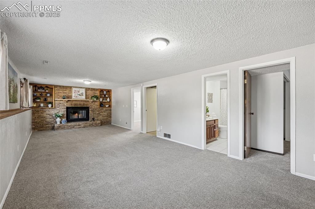 Image 5 of 44: Lower level family room with fireplace and built in shelves. New carpet and