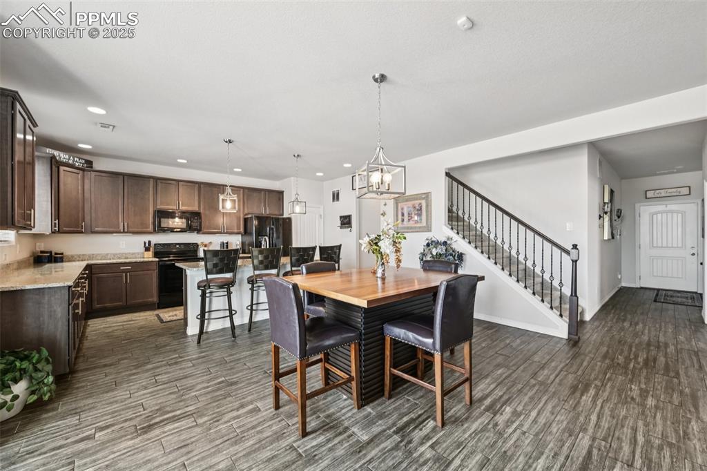Image 11 of 44: Dining room with wood finished floors, stairs, recessed lighting, and a cha