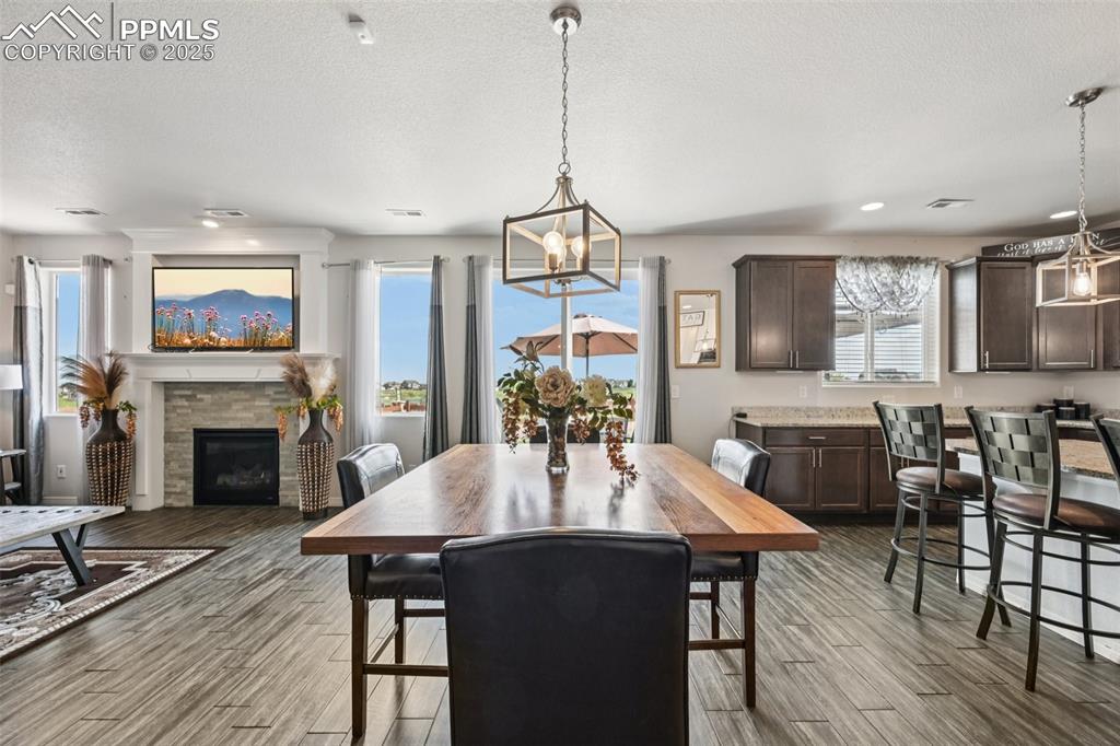 Image 12 of 44: Dining space with wood finished floors, a glass covered fireplace, a textur