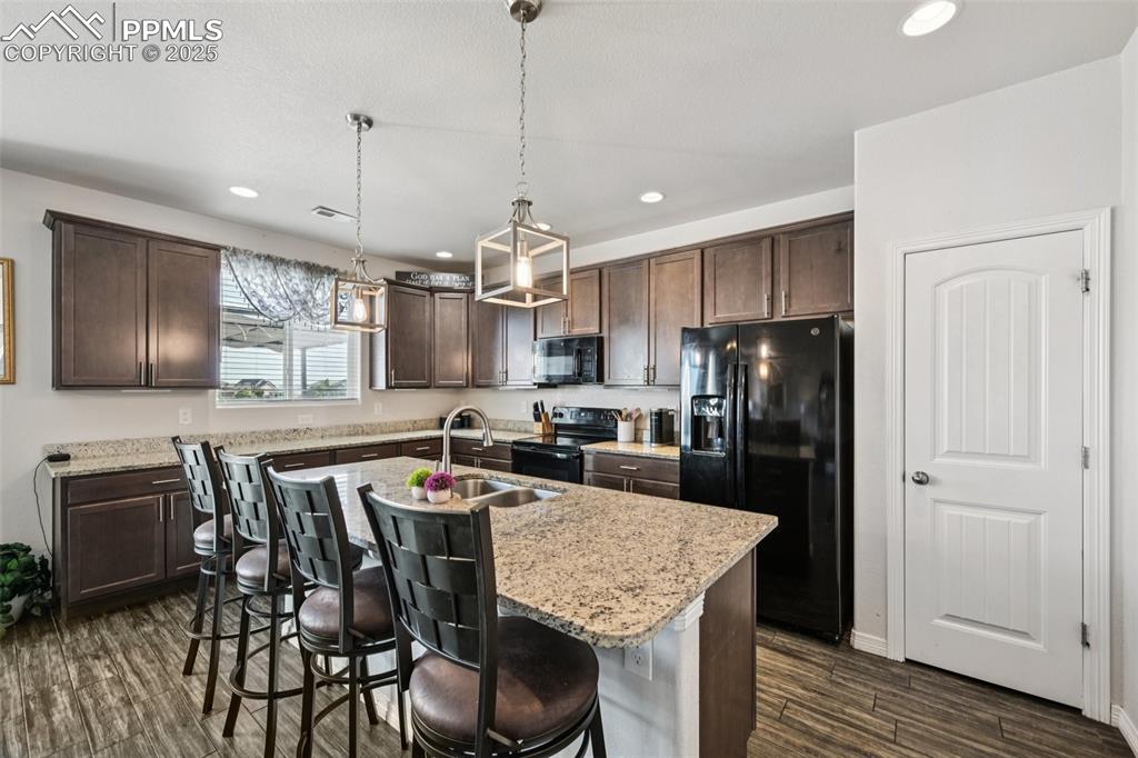 Image 14 of 44: Kitchen featuring black appliances, dark brown cabinetry, recessed lighting