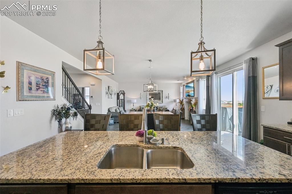 Image 17 of 44: Kitchen featuring open floor plan, dark brown cabinetry, hanging light fixt