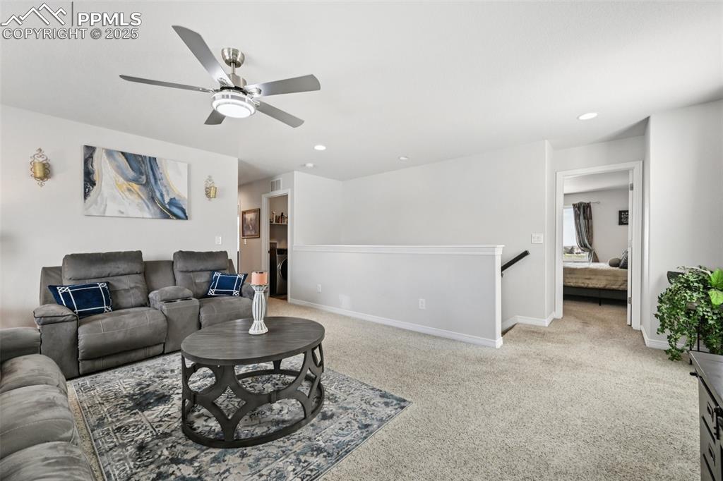 Image 22 of 44: Living room with ceiling fan, light colored carpet, and recessed lighting