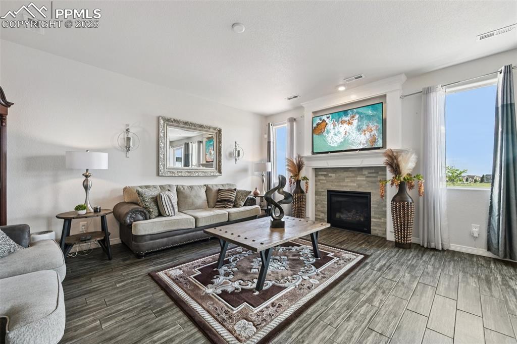 Image 8 of 44: Living area with wood finished floors, a glass covered fireplace, and reces