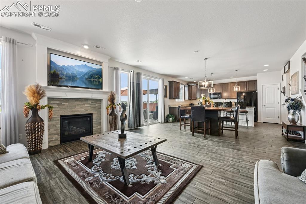 Image 9 of 44: Living area with wood finished floors, recessed lighting, a stone fireplace