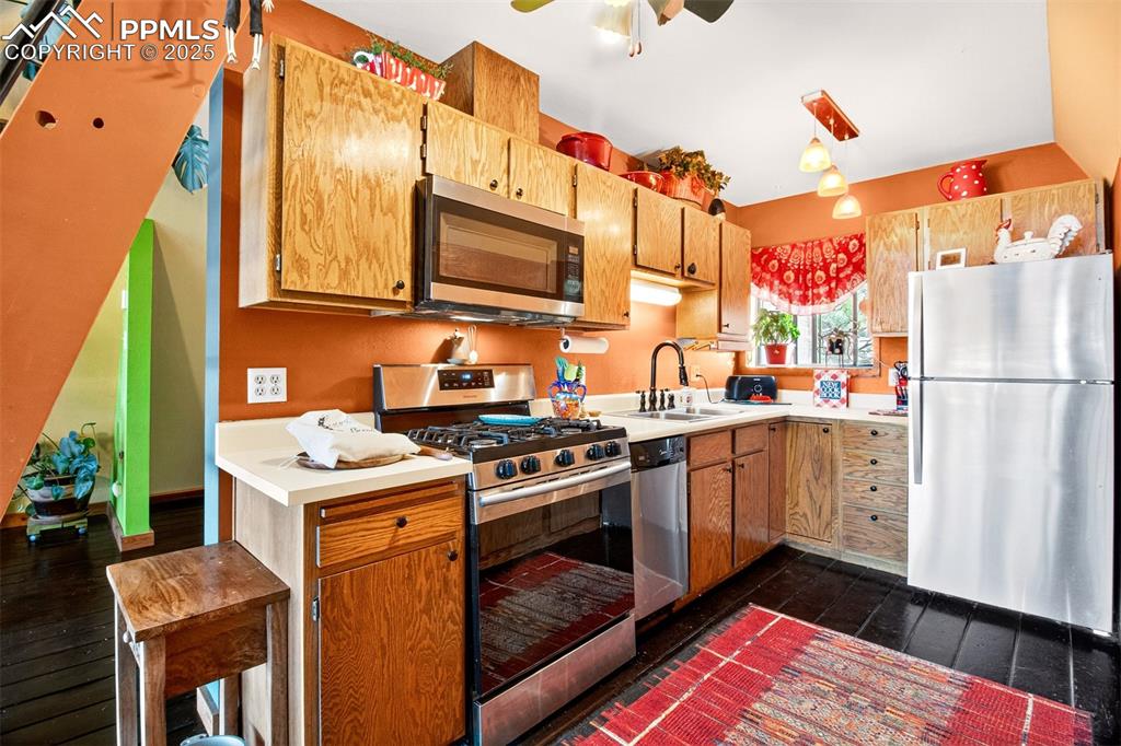 Image 14 of 42: Kitchen with appliances with stainless steel finishes, dark wood-style floo