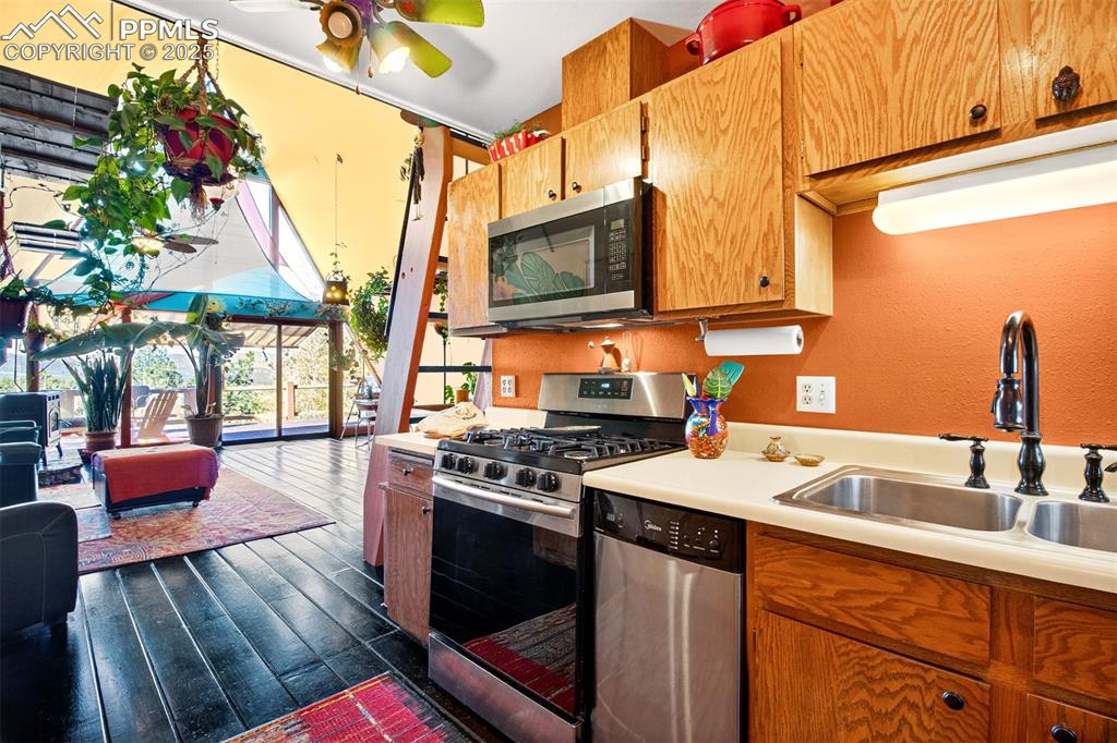 Image 15 of 42: Kitchen with appliances with stainless steel finishes, brown cabinetry, dar