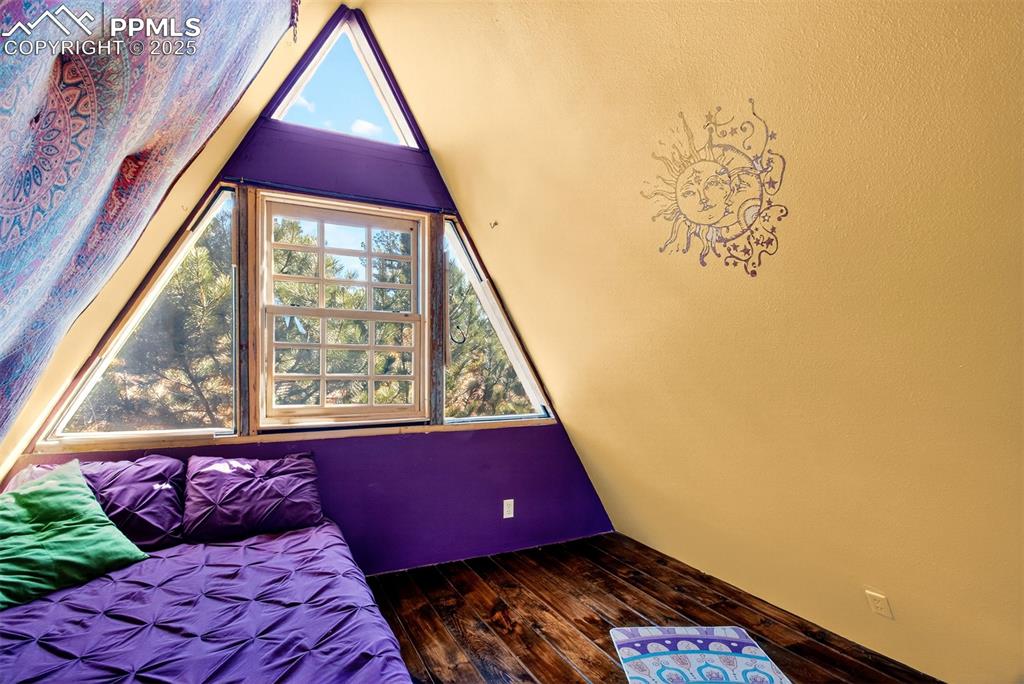 Image 16 of 42: Bedroom featuring dark wood finished floors and lofted ceiling