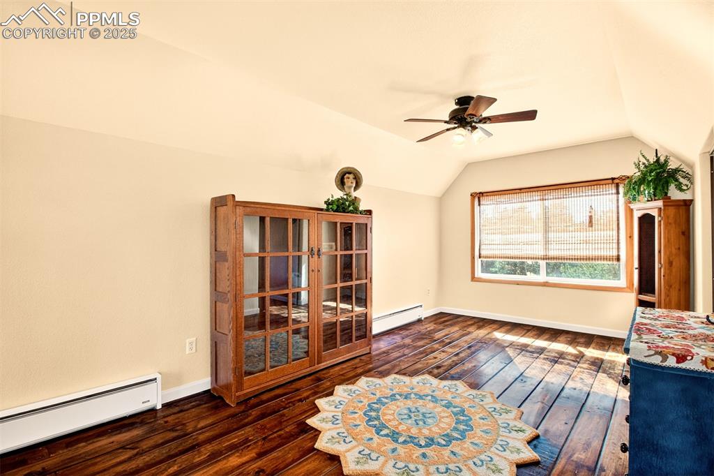 Image 31 of 42: Unfurnished room with a baseboard heating unit, lofted ceiling, dark wood-s
