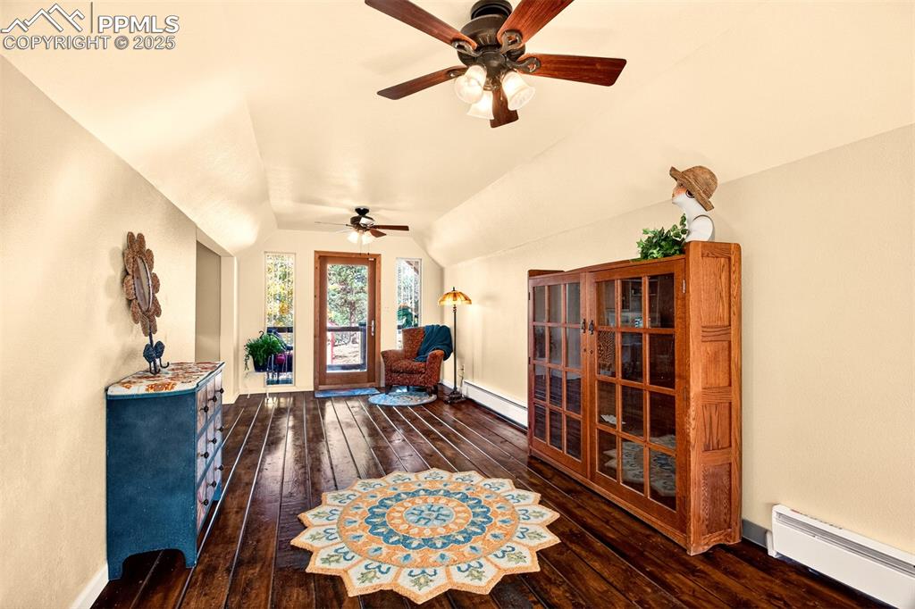 Image 32 of 42: Living area with a baseboard radiator, dark wood finished floors, lofted ce