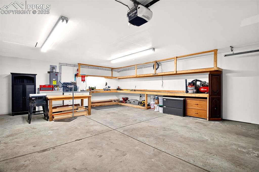 Image 35 of 42: Garage with a workshop area and a garage door opener