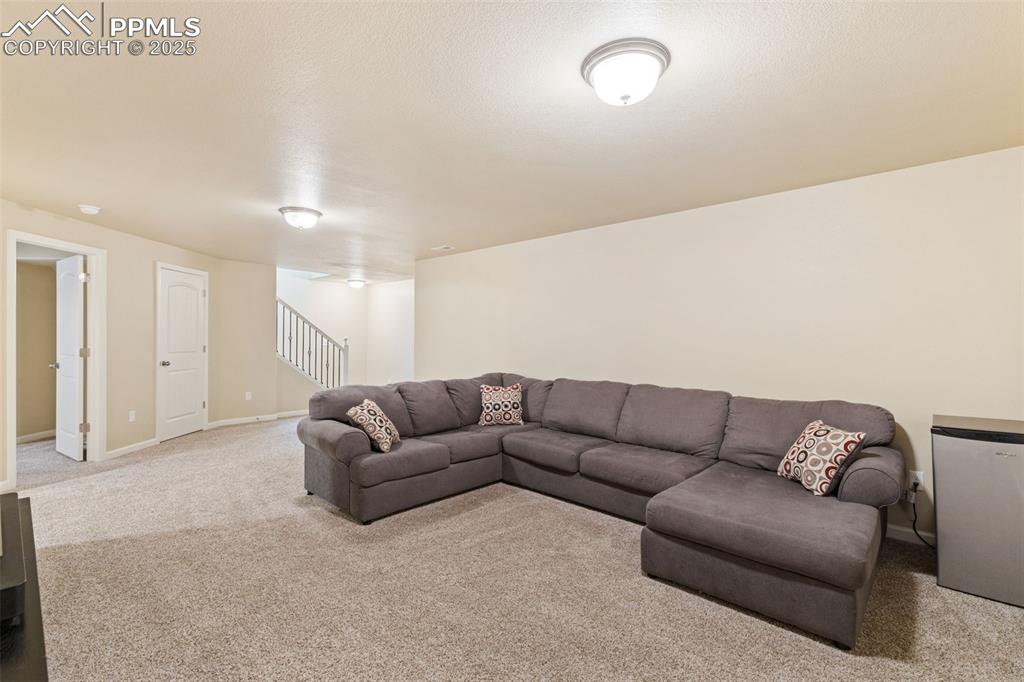 Image 12 of 33: Carpeted living area with stairs and a textured ceiling
