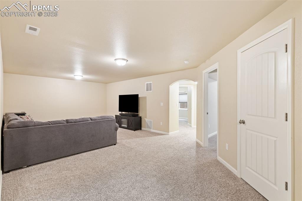 Image 13 of 33: Living area featuring light carpet and arched walkways